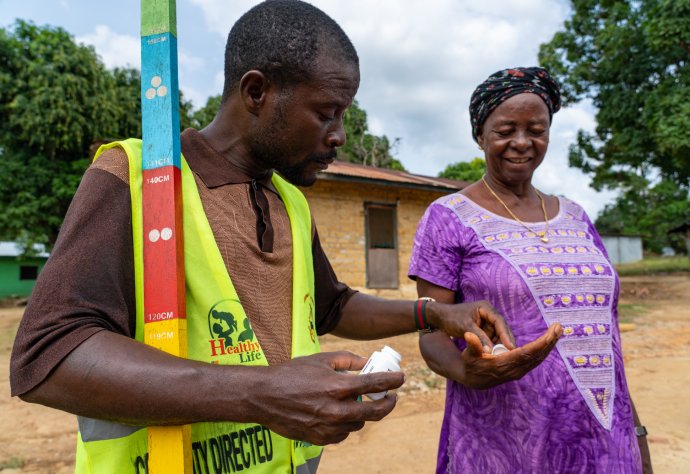 Community Volunteer Victor Scott gives Hawa Barclay treatment to protect her against onchocerciasis in Gbarpolu Liberia. Photo: Sightsavers/ Carielle Doe