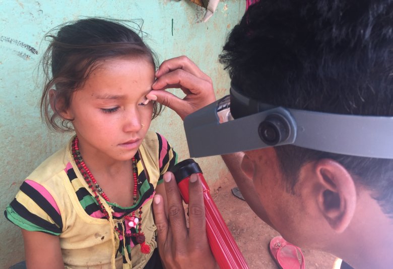 Credit: RTI International, ENVISION project, Nepal   Caption: Taken during Trachoma Surveillance Survey in Baitadi district of Nepal, 2017. Pictured are Narendra Sharma (grader performing the survey) and Rama Chettri, 8 years of age. 