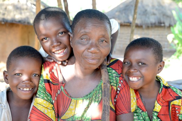 Berthine (64) is blind due to onchocerciasis, with her grandchildren. DRC. CBM/Tobias Pflanz