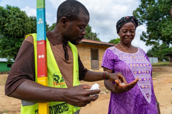 Community Volunteer Victor Scott gives Hawa Barclay treatment to protect her against onchocerciasis in Gbarpolu Liberia. Photo: Sightsavers/ Carielle Doe