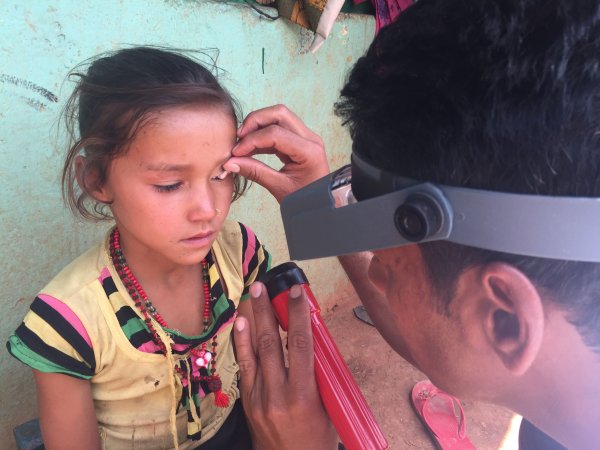 Credit: RTI International, ENVISION project, Nepal     Caption: Taken during Trachoma Surveillance Survey in Baitadi district of Nepal, 2017. Pictured are Narendra Sharma (grader performing the survey) and Rama Chettri, 8 years of age.  
